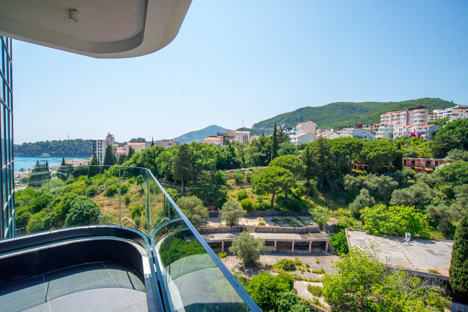 Panoramic view from the balcony of a modern apartment in Bečići, Montenegro: sea, mountains, and the green landscape of the resort.
