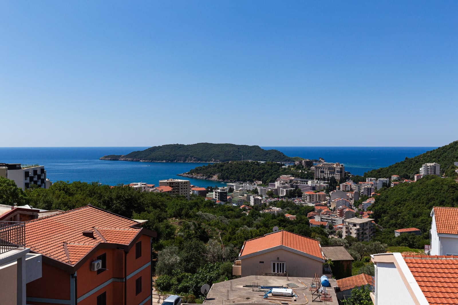 Panoramic sea view of the island of Sveti Nikola from a villa in Bečići, Montenegro: urban development and green hills.