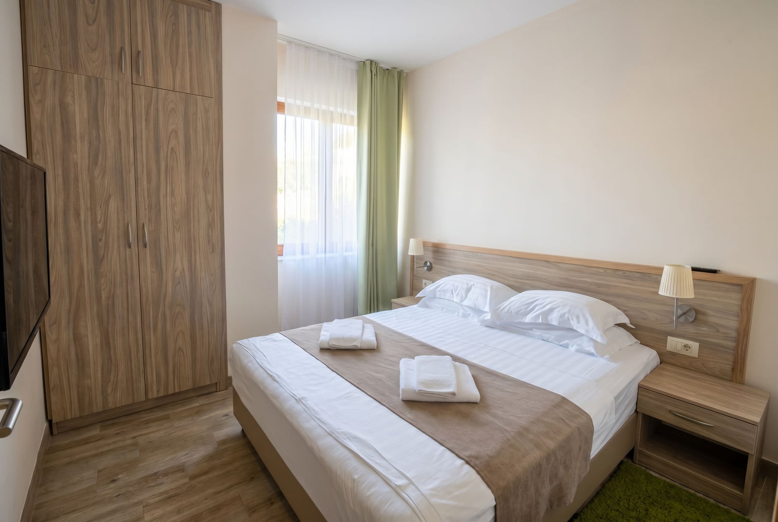 Cozy bedroom with a double bed and wardrobe in an apartment, Bečići, Montenegro: modern interior and light tones.