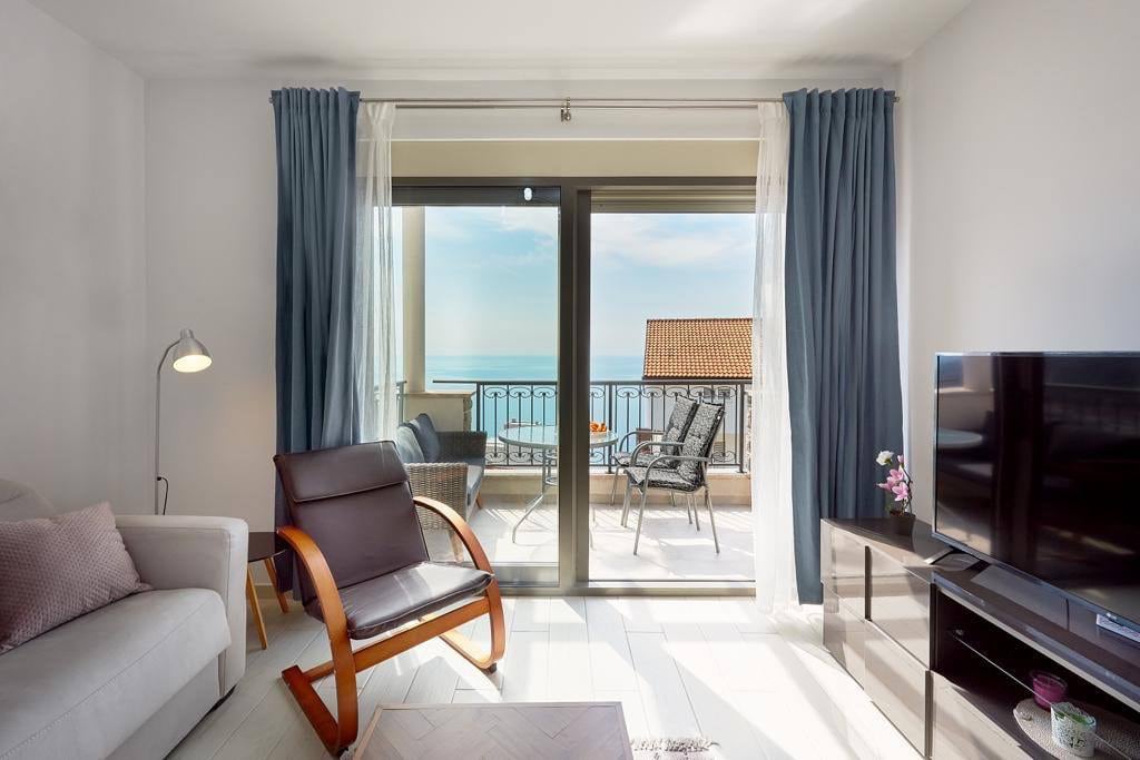 Living room in an apartment in Pržno, Montenegro: sea view from the terrace, modern furniture, TV area, and floor-to-ceiling windows.