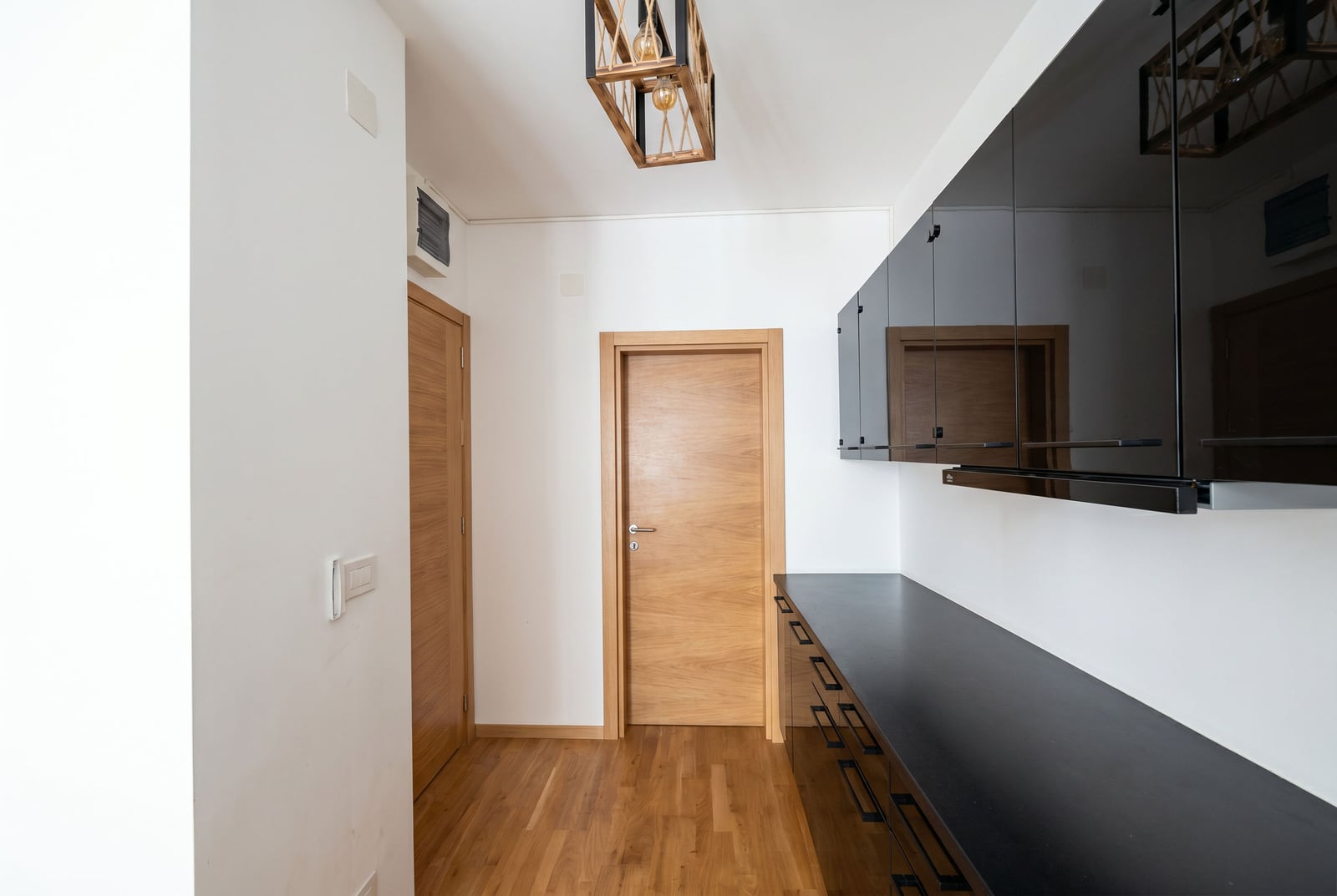Modern kitchen with glossy black cabinets in an apartment, Bečići, Montenegro: stylish interior and wooden doors.