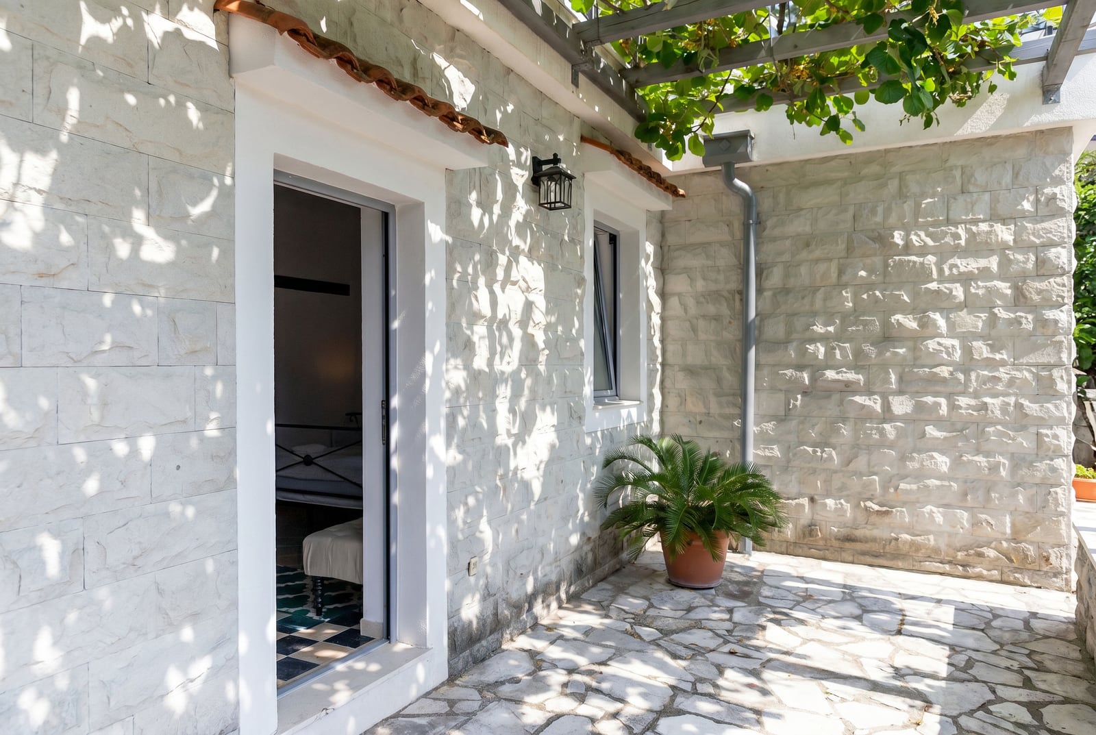Stone terrace with a pergola at the apartments in Risan, Montenegro: view of the apartment entrance and a cozy inner courtyard.