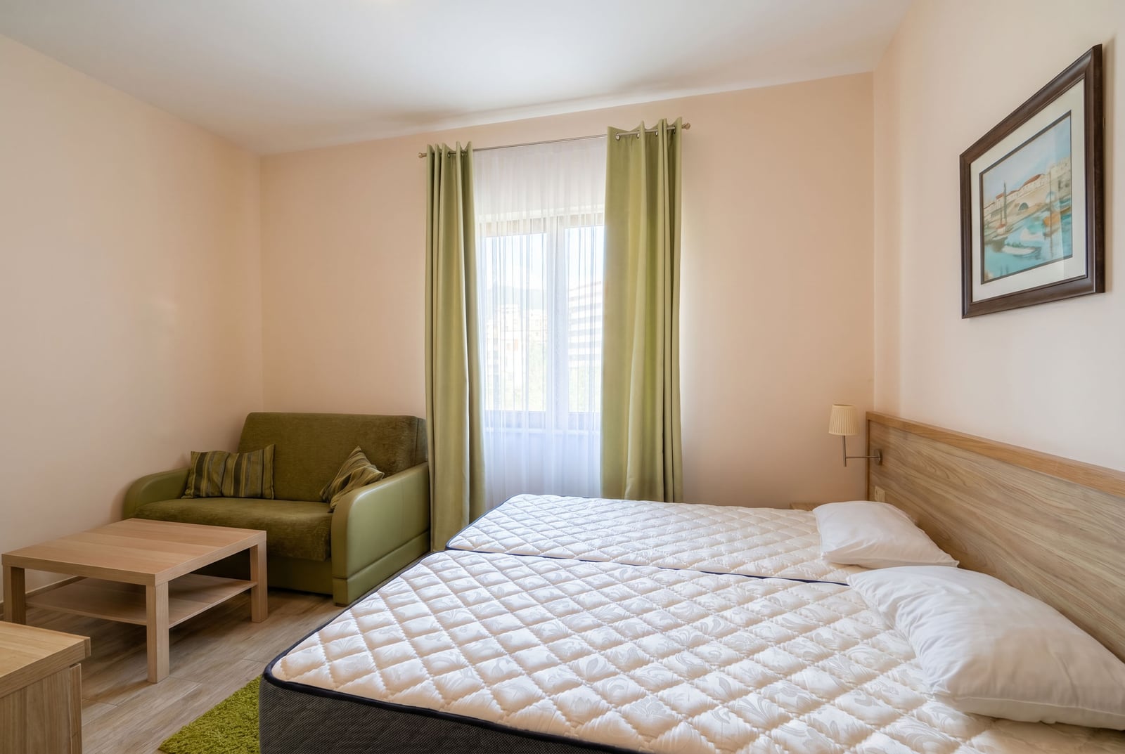 Bright bedroom with a double bed and a green sofa in an apartment, Becici, Montenegro.