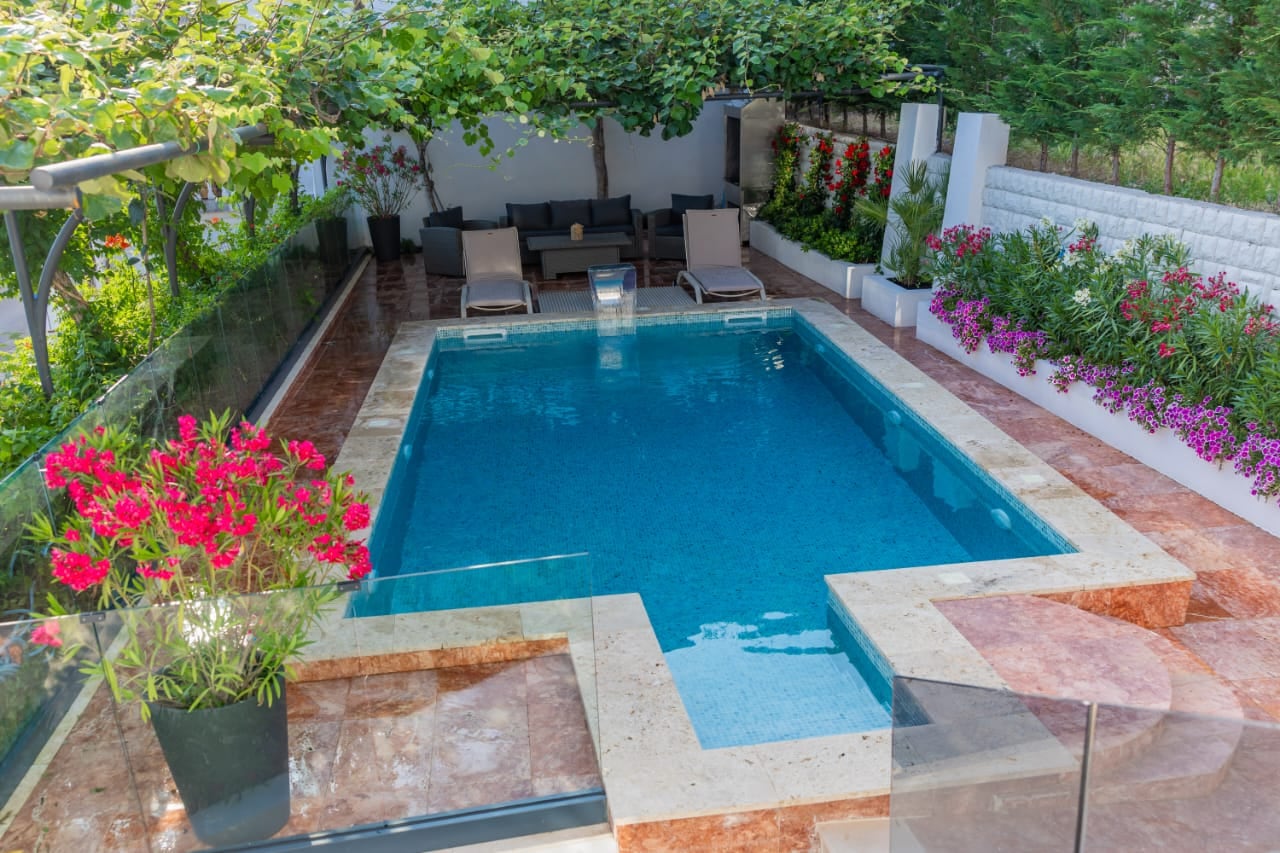 Private pool with a lounge area and terrace at a villa in Budva, Montenegro: sun loungers, garden, and landscape design.