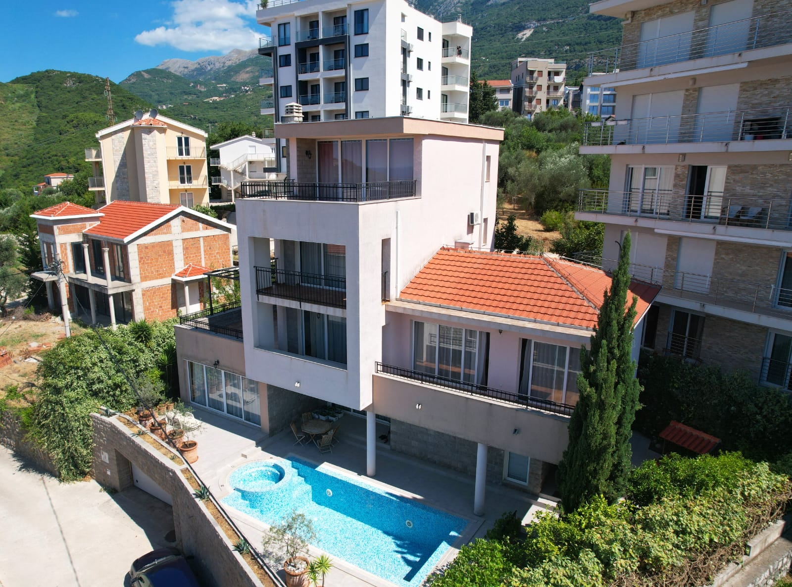 Modern villa with a swimming pool and terraces in Bečići, Montenegro: view of the building with panoramic windows and mountains.