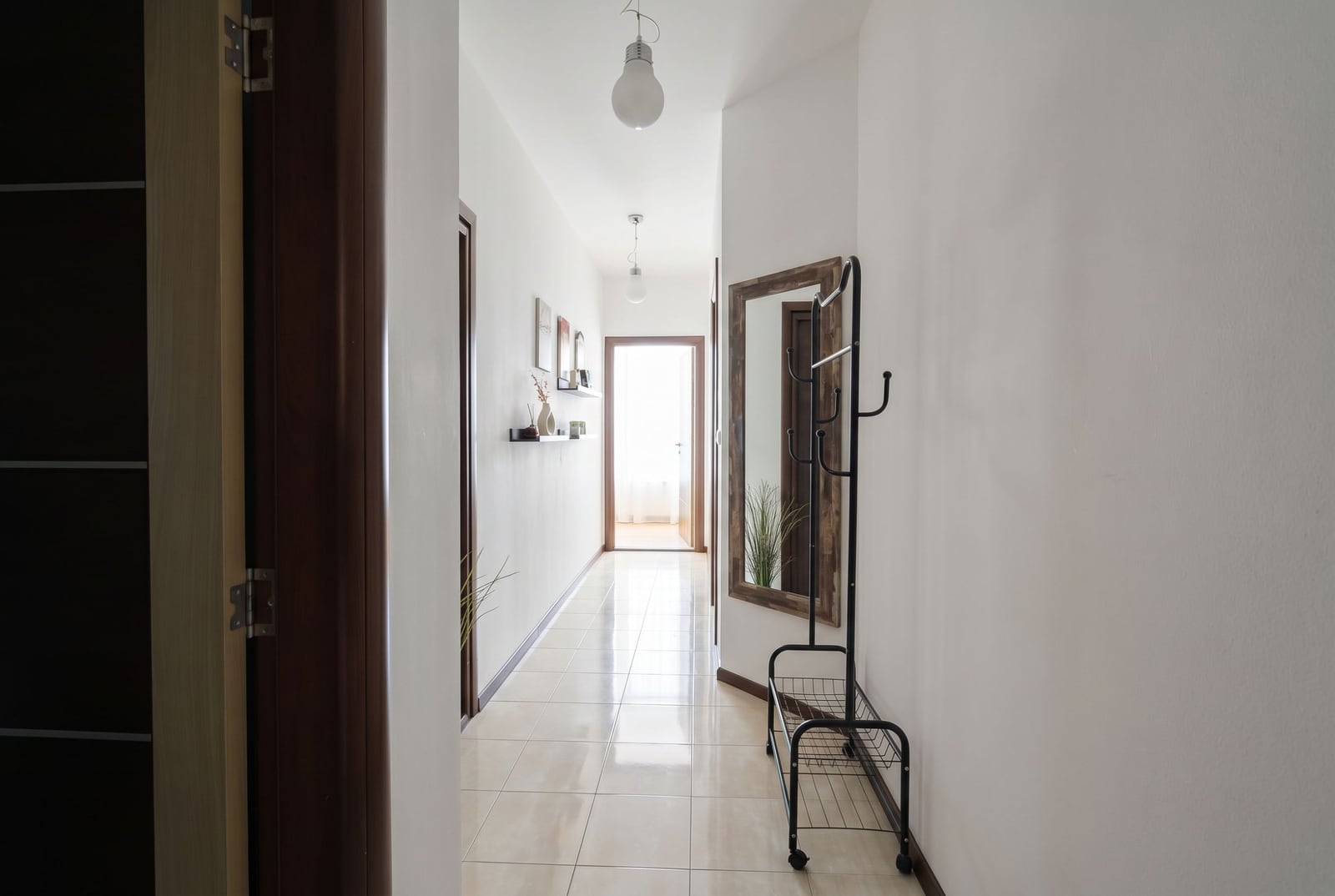 Bright hallway in an apartment in Budva, Montenegro: tiled floor, framed mirror, coat rack, and access to the balcony.