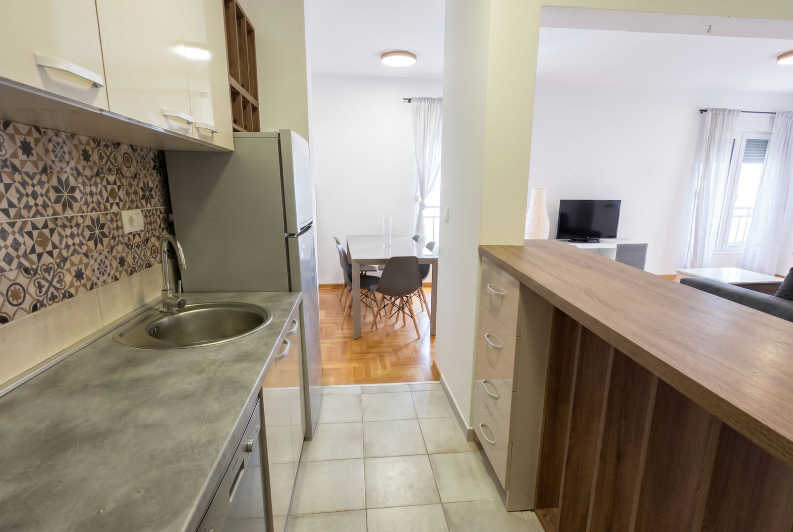 Modern kitchen with a breakfast bar and dining area in an apartment, Budva, Montenegro. Interior with tile and furniture.