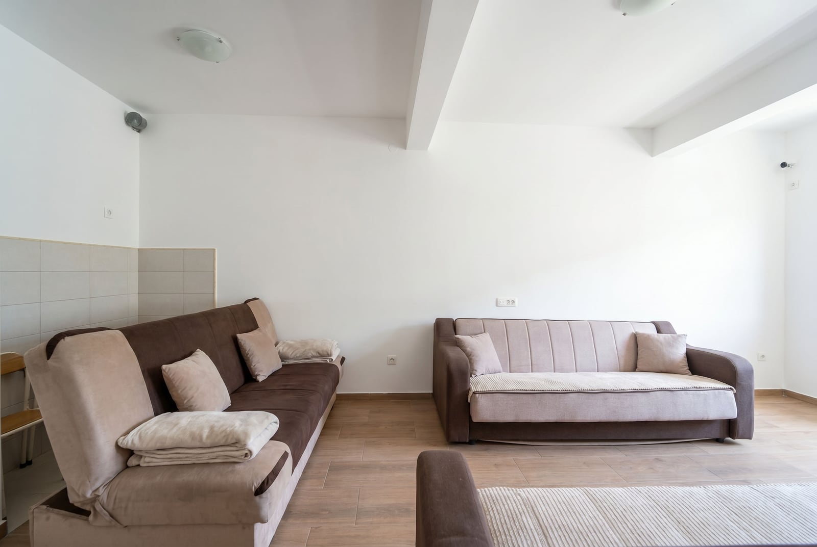 Bright living room with two sofas in an apartment for sale in Budva, Montenegro: modern interior, laminate flooring, white walls.