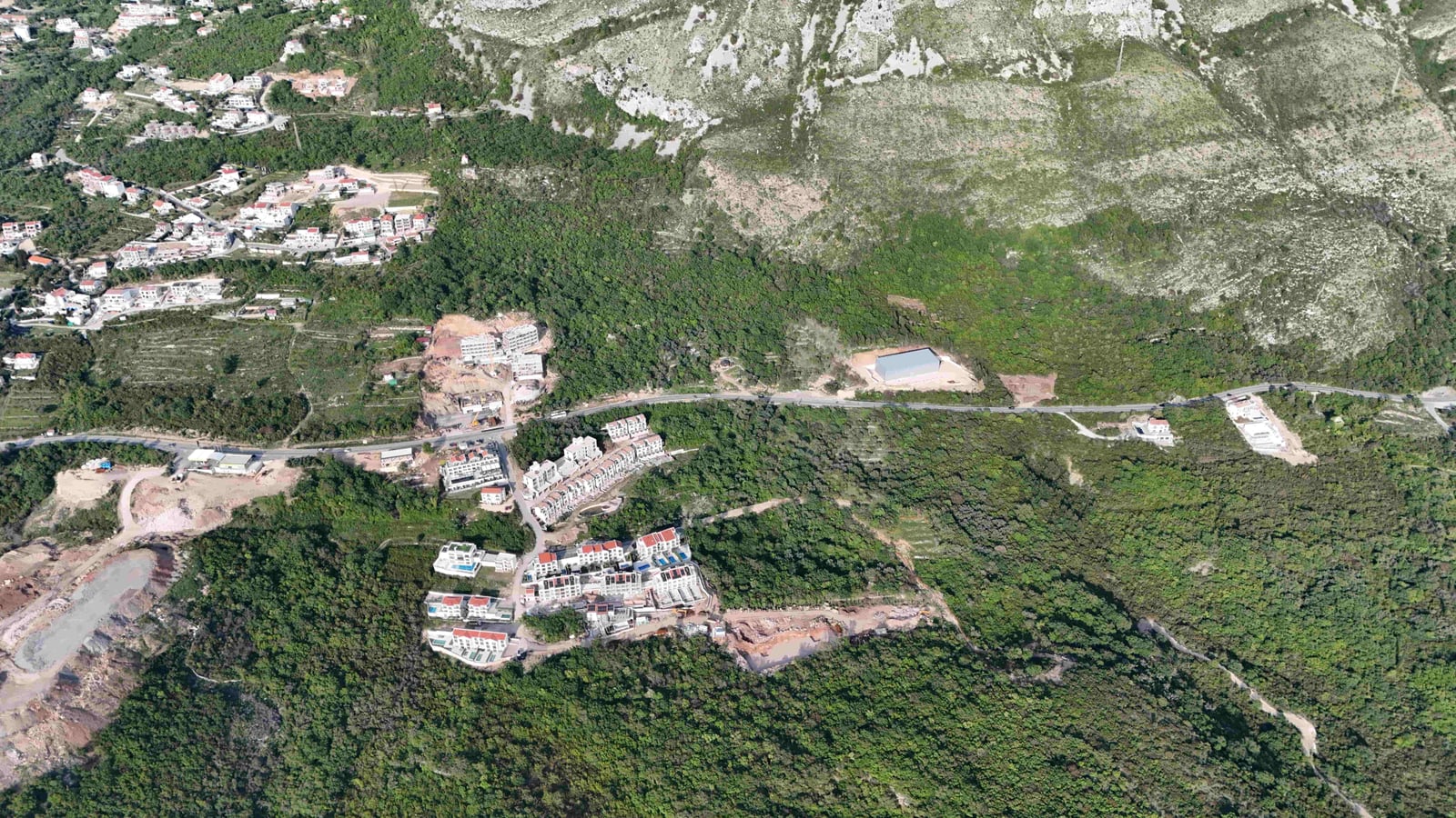 Aerial view of a land plot and residential complex in Markovići, Montenegro, surrounded by mountains and forest.
