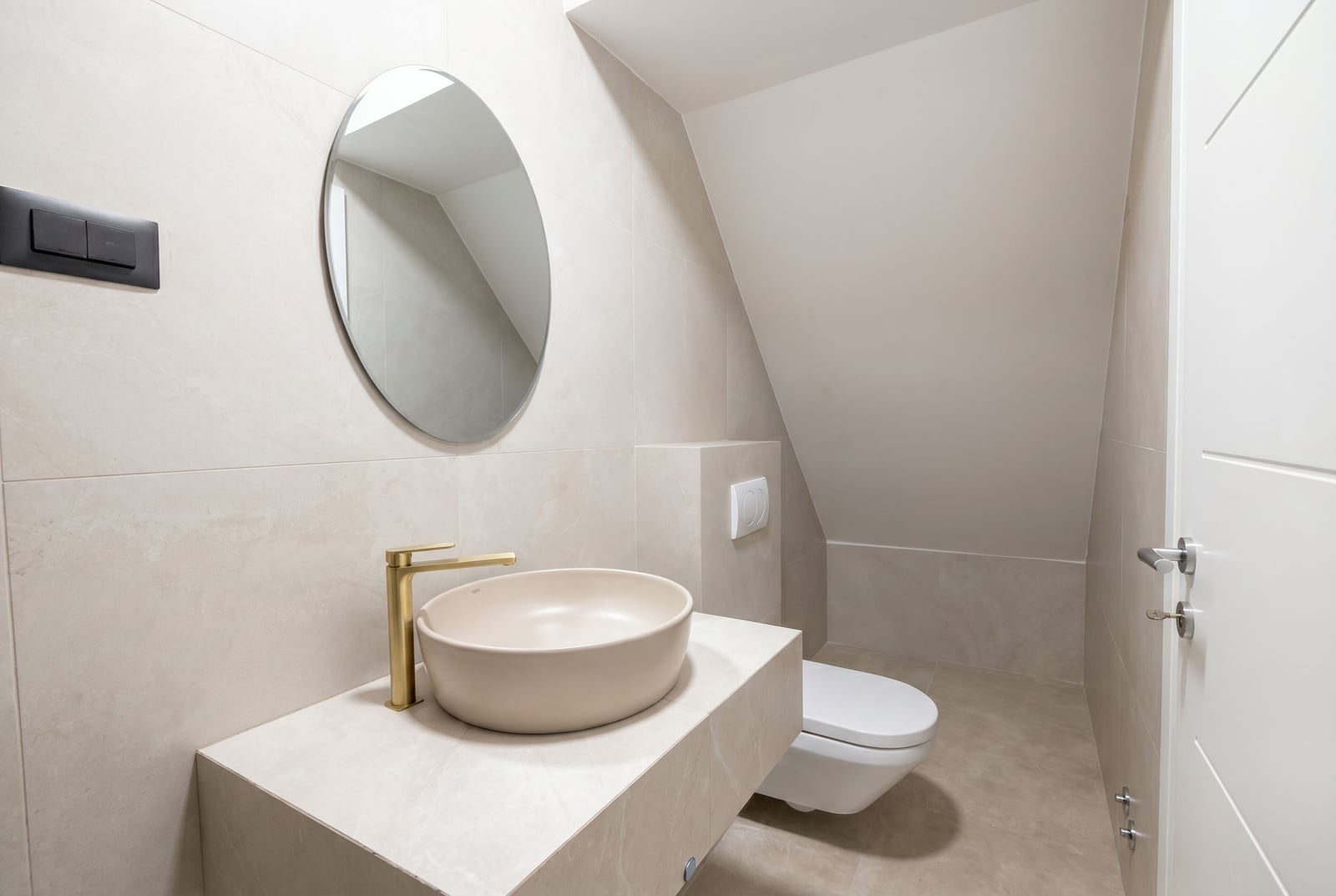 Modern bathroom in a Budva, Montenegro office: beige tiles, vessel sink, and gold faucet.