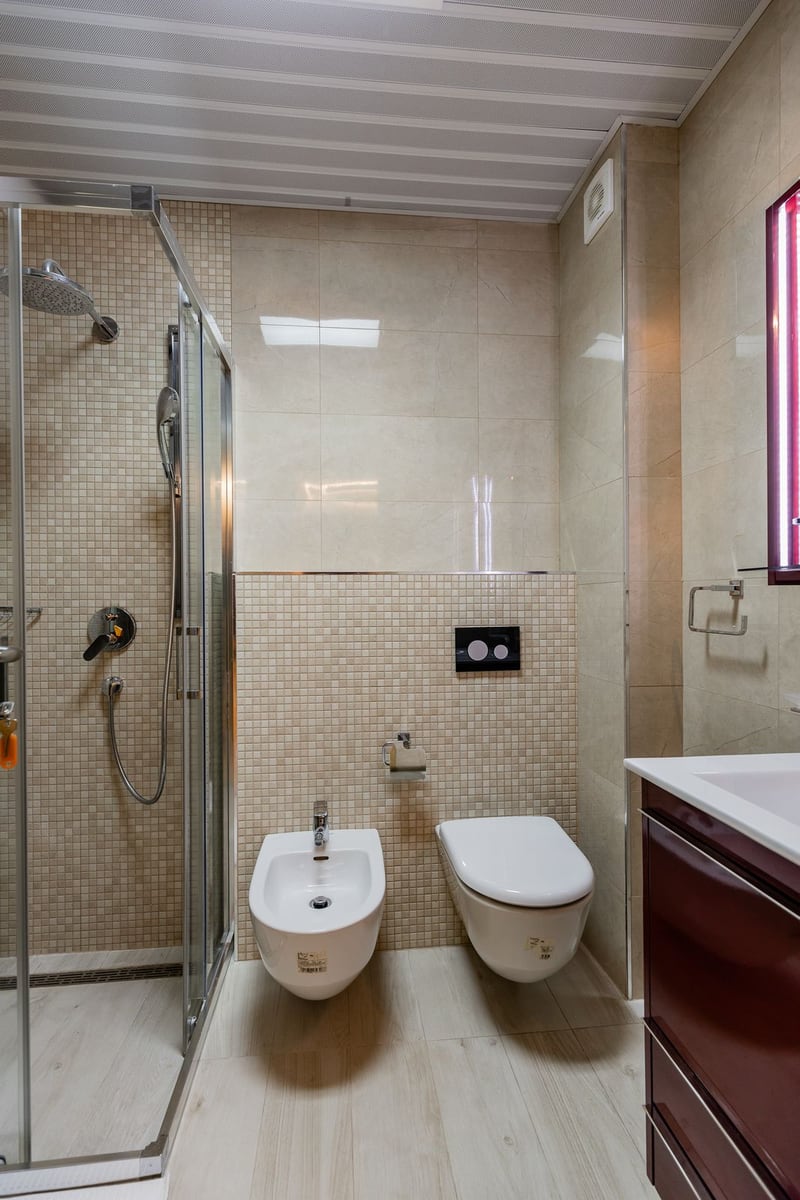 Modern bathroom in a penthouse in Pržno, Montenegro: shower cabin, wall-hung toilet and bidet, beige tiles.