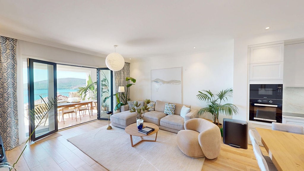 Bright living room with sea view in an apartment, Luštica, Montenegro: modern furniture, terrace, and kitchen.