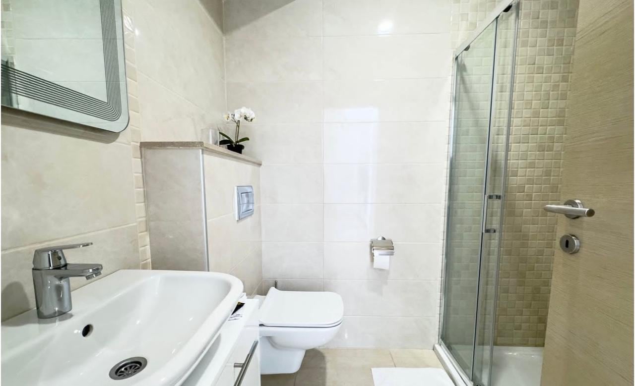 Modern bathroom with a walk-in shower in an apartment, Bečići, Montenegro: light-colored tiles and high-quality fixtures.