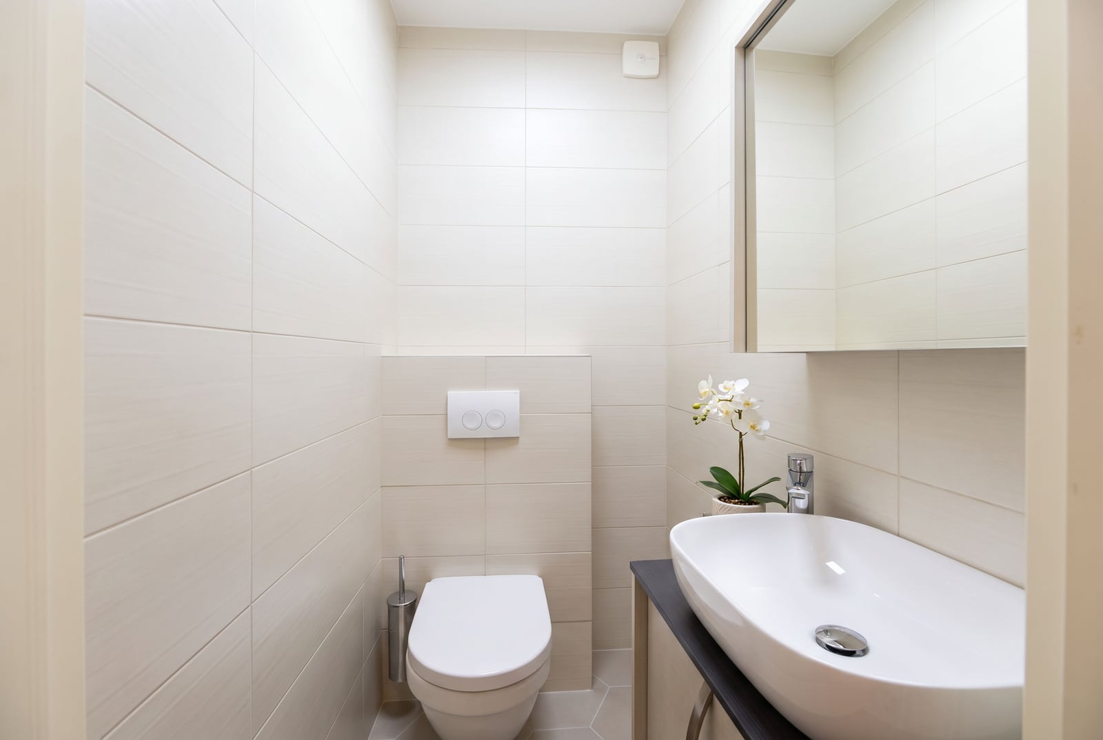 Modern bathroom in an apartment in Dobrota, Montenegro: light tiles, a vessel sink, and a wall-hung toilet.