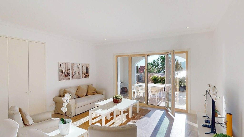 Bright living room with terrace access in an apartment, Luštica, Montenegro: white furniture, modern interior, and garden view.
