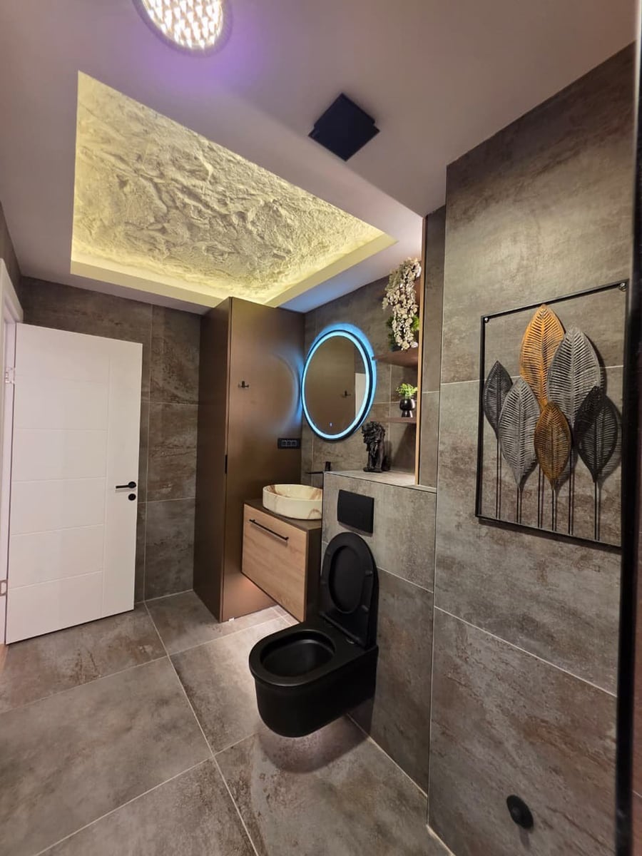 Modern bathroom in an apartment, Becici, Montenegro: stylish stone-look finishes, black fixtures, and lighting.