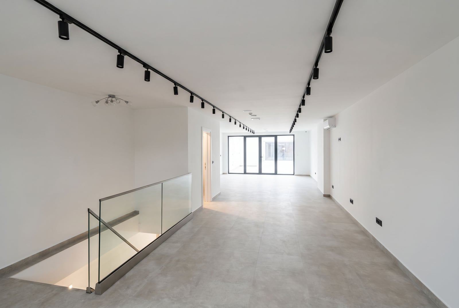 Modern office in Budva, Montenegro: bright space with track lighting, glass partitions, and tiled flooring.