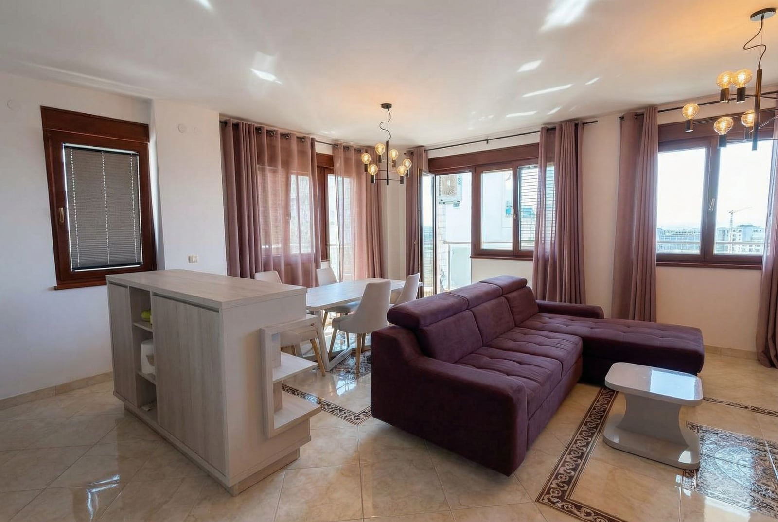 Bright living room with a purple sofa, dining area, and panoramic windows in an apartment, Becici, Montenegro.