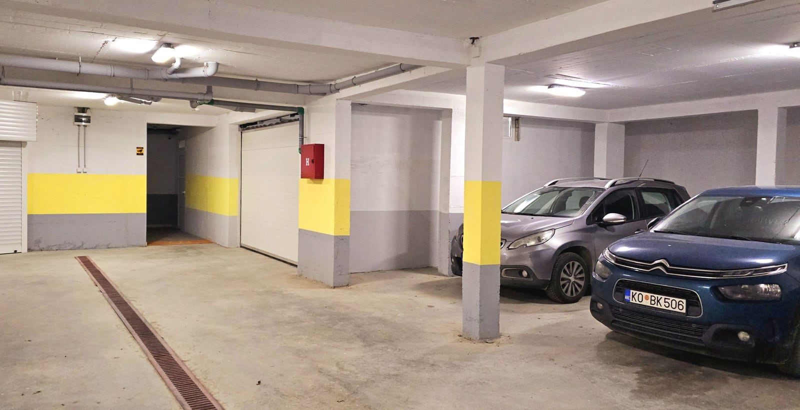 Covered underground parking in a residential complex in Tivat, Montenegro: parking spaces with concrete flooring and lighting.