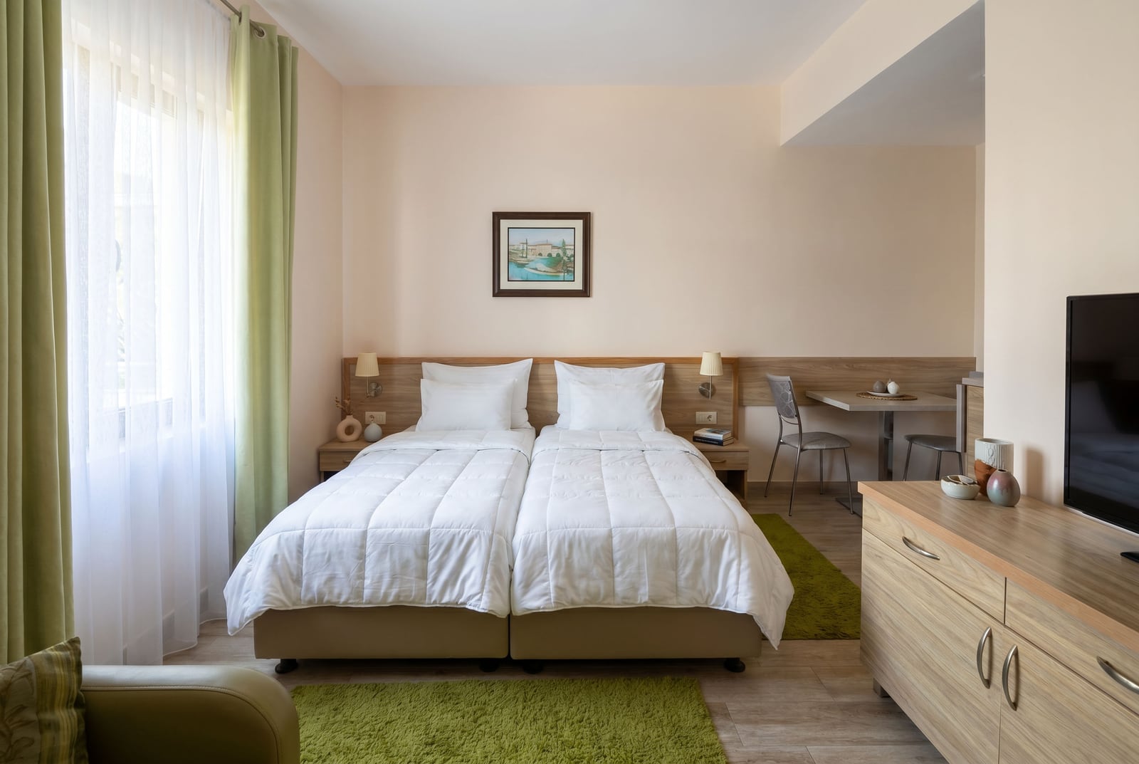 Cozy twin bedroom in a Becici apartment, Montenegro: bright interior, TV, dining area, and window view.