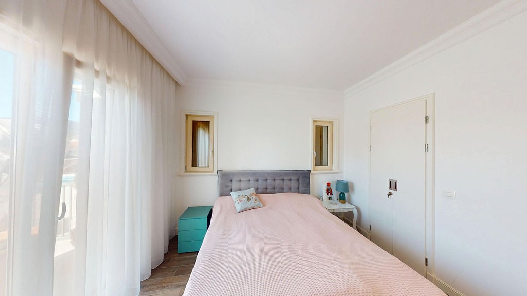 Bright bedroom with a double bed in an apartment in Luštica, Montenegro: panoramic window and modern interior.