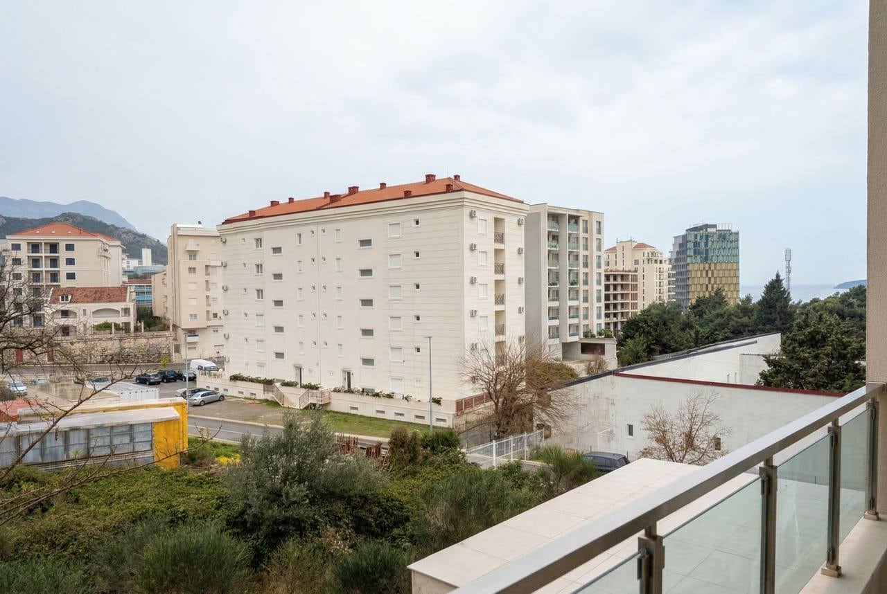 View from the balcony of an apartment in Becici, Montenegro: a panorama of the residential area, greenery, and the sea horizon.