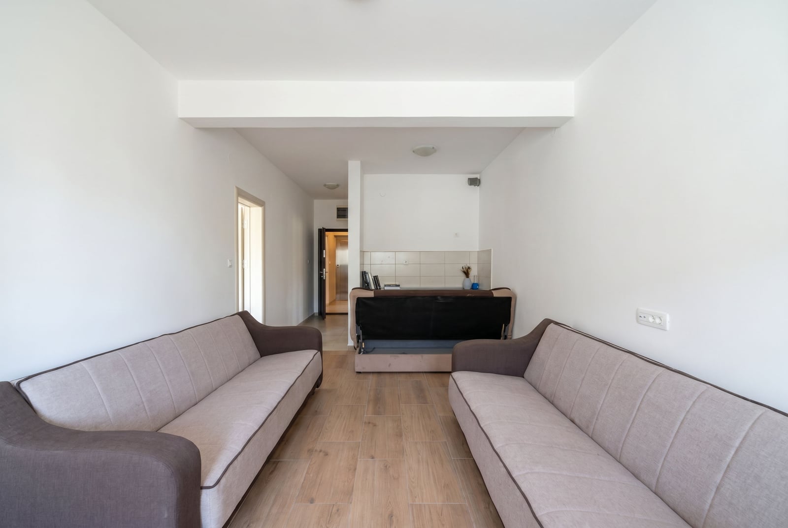 Living room with two sofas and a kitchen area in an apartment for sale in Budva, Montenegro, bright interior.