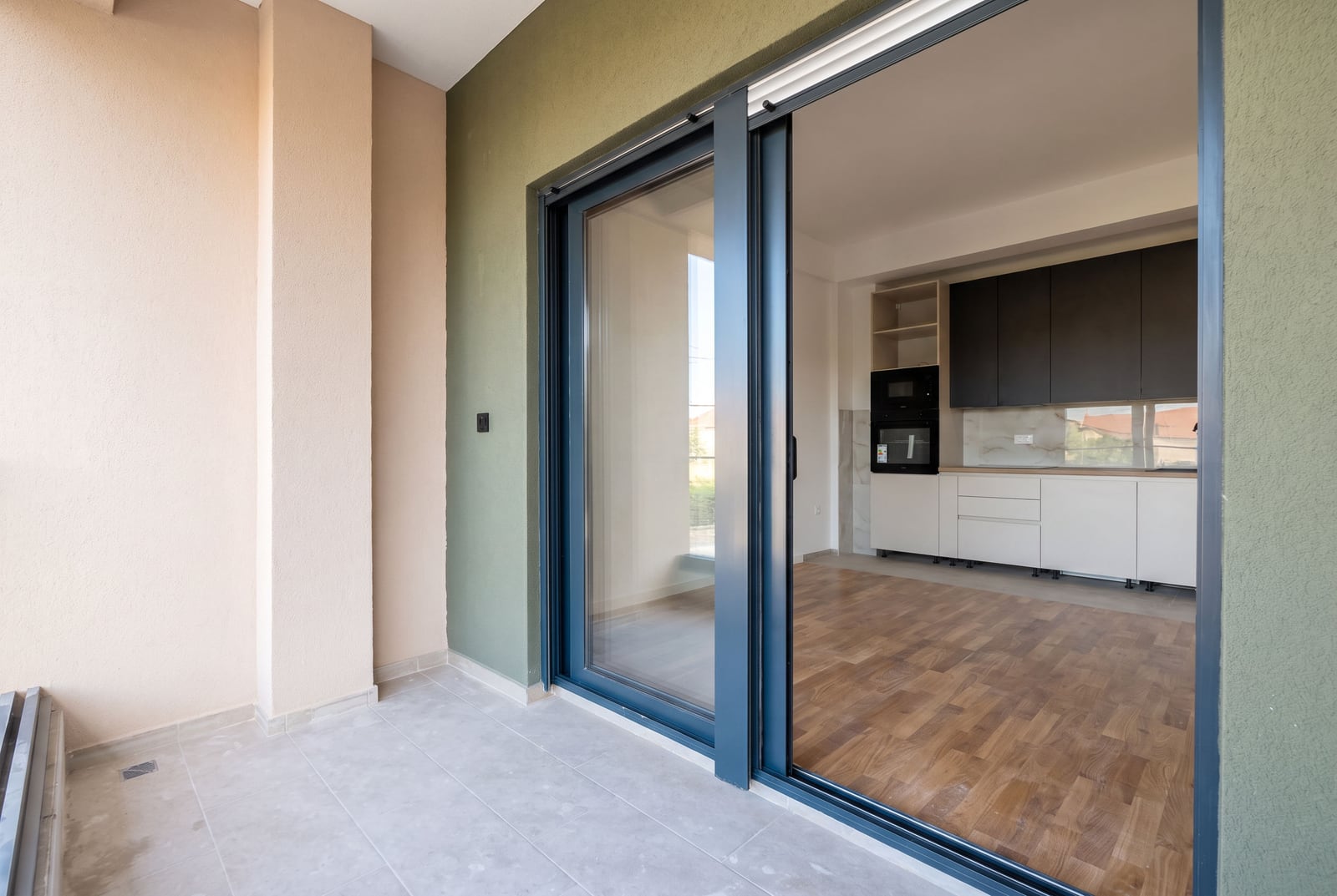 Wide sliding doors to the balcony of a modern apartment with a kitchen in the city of Bar, Montenegro.