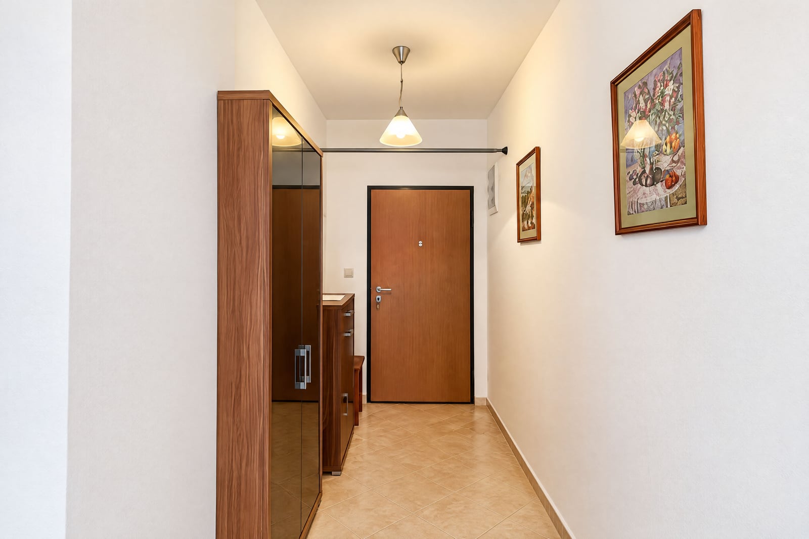 Entry hallway featuring a wooden door, mirrored wardrobe, pendant light, and framed artwork on white walls.