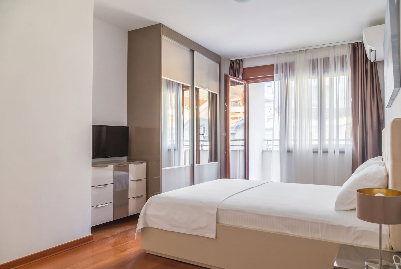 Bright bedroom with a double bed, wardrobe, and balcony access in an apartment in Becici, Montenegro.