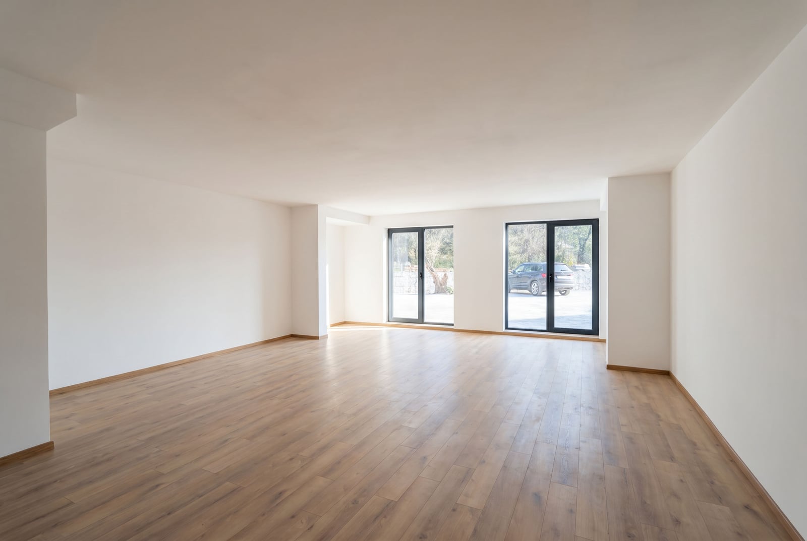 Spacious living room with laminate flooring and panoramic windows in an apartment in Pržno, Montenegro. Bright space ready for renovation.