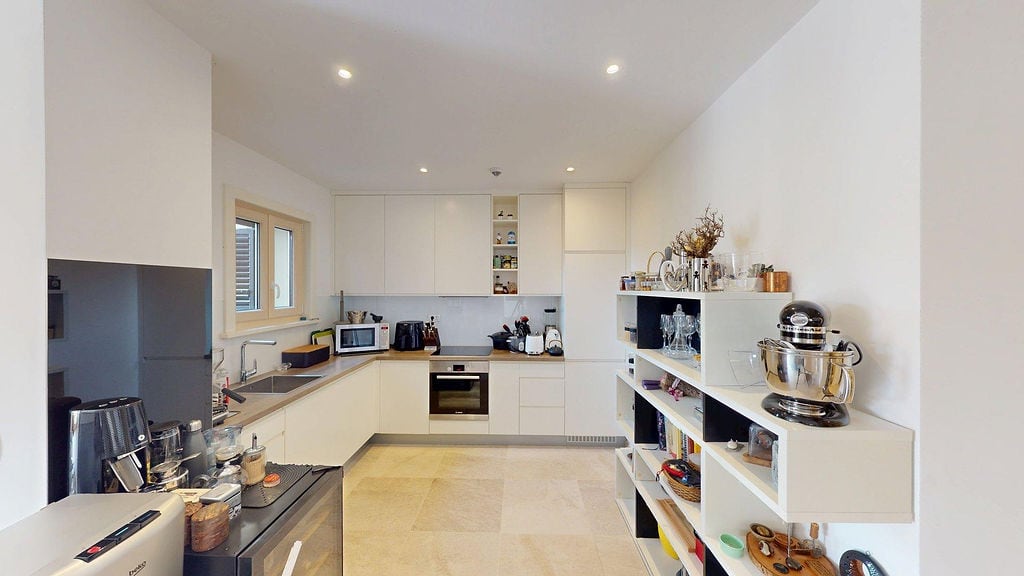 Modern bright kitchen in an apartment, Luštica, Montenegro: white facades, built-in appliances, and open shelving.