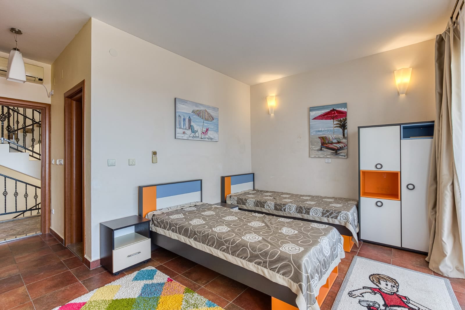 Bedroom with two beds, a wardrobe, and vibrant decor in a villa in Becici, Montenegro. Cozy interior for relaxation.