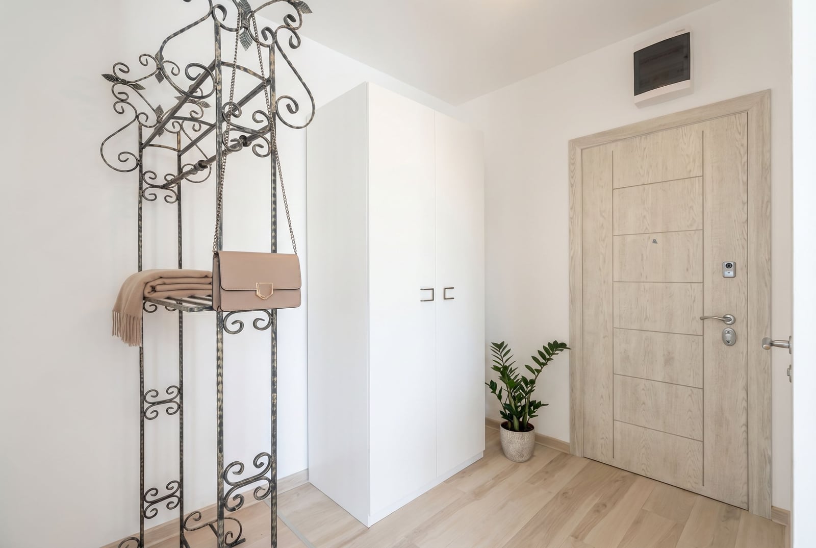 Bright hallway in an apartment, Becici, Montenegro: white wardrobe, wrought-iron coat rack, and an interior door in light wood.