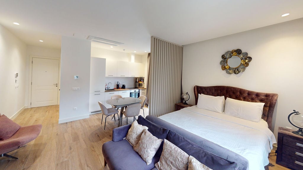 Modern bedroom with a double bed and kitchen in the Luštica apartments, Montenegro: stylish interior, light tones.