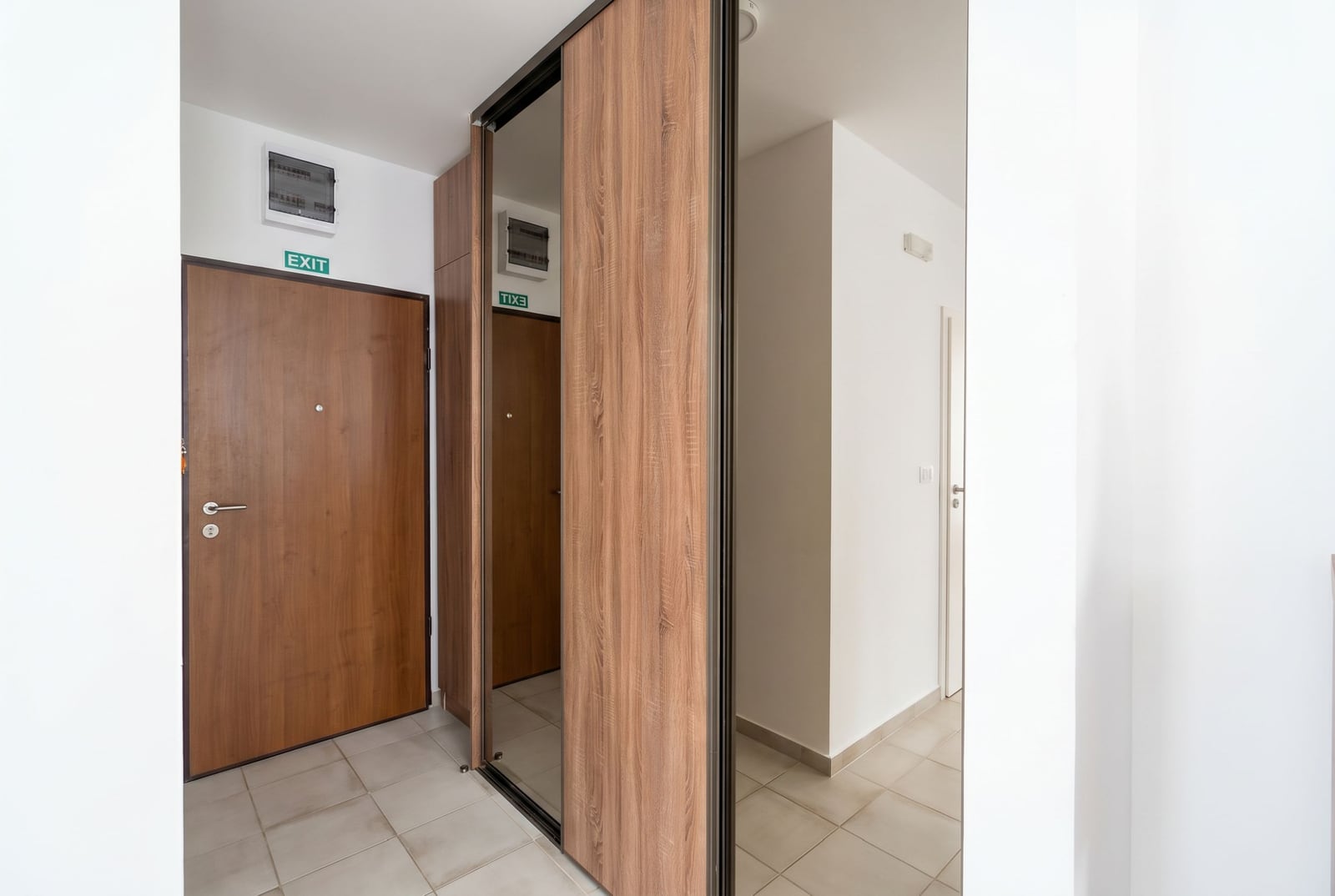 Hallway in an apartment in Budva, Montenegro: built-in wardrobe with mirrored doors, light tile, and the entrance door.