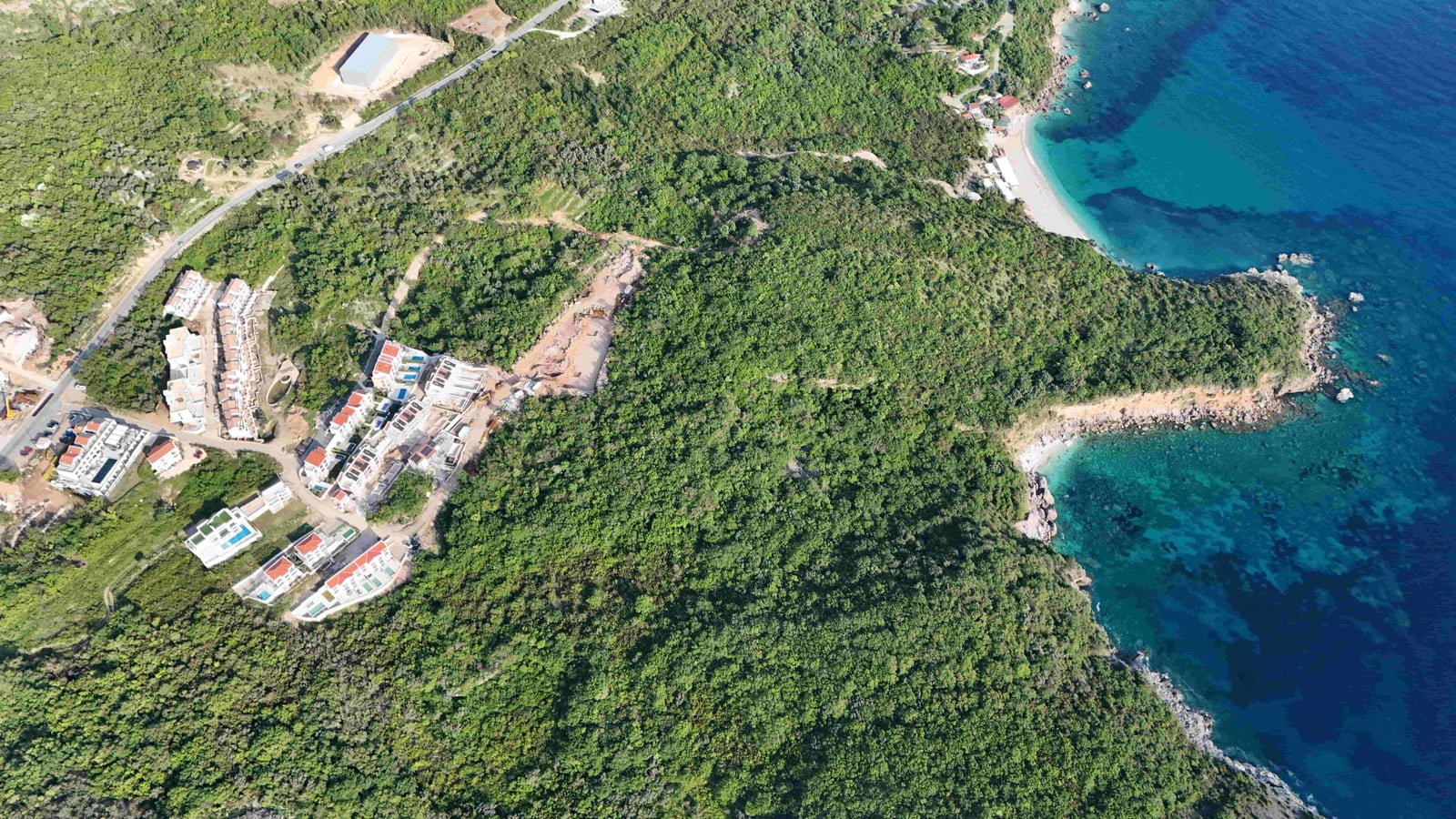Aerial view of a land plot and villas in Reževići, Montenegro, with a panoramic view of the Adriatic Sea.