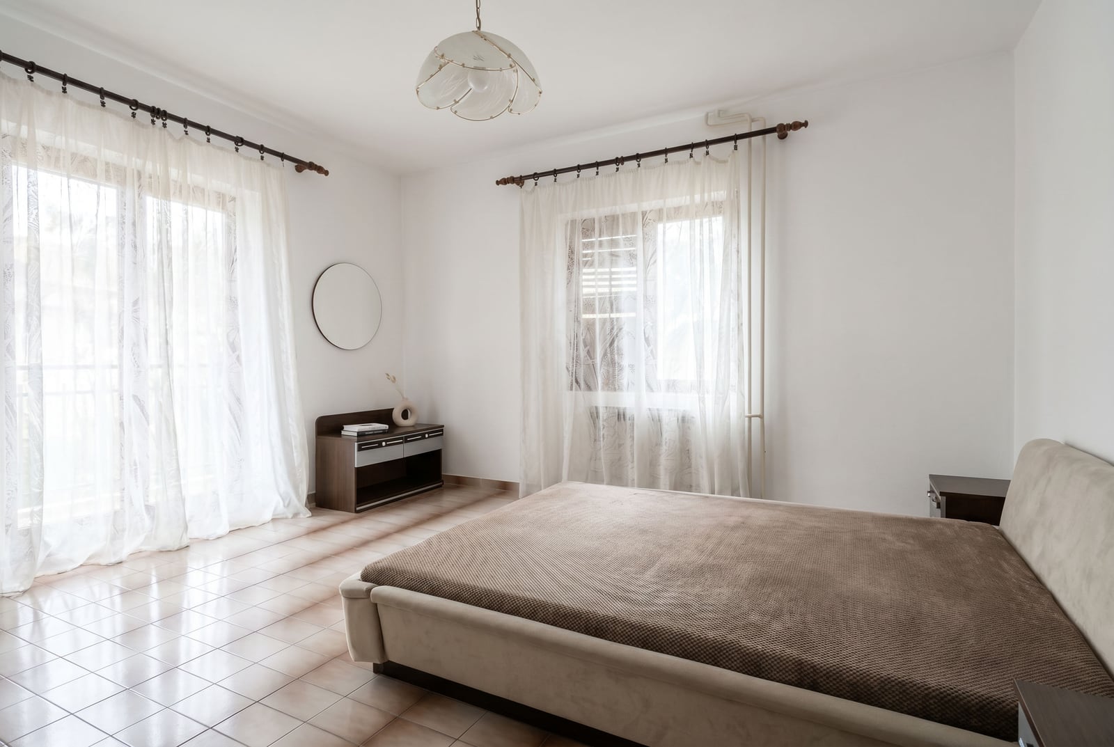 Bright bedroom with a double bed and balcony access in a house, Lastva, Montenegro. Tiled floor, panoramic windows.