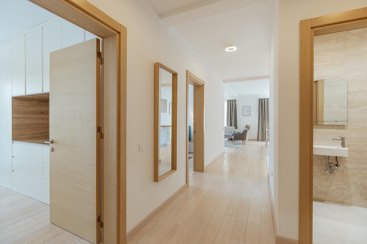 Bright hallway in a modern apartment in Igalo, Montenegro: built-in wardrobe, mirror, and entrance to the bathroom.