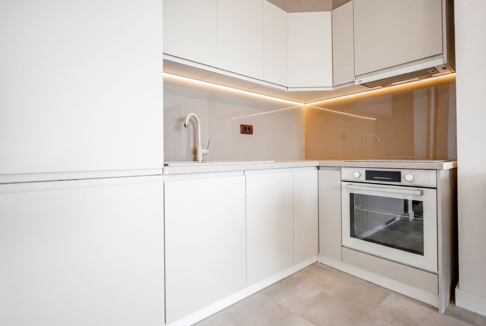 Modern bright kitchen with white cabinetry and built-in appliances in an apartment, Sveti Stefan, Montenegro.