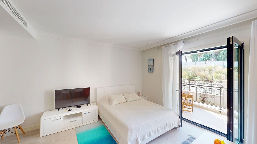 Bright bedroom with a double bed and balcony access in Luštica apartments, Montenegro. Modern interior.