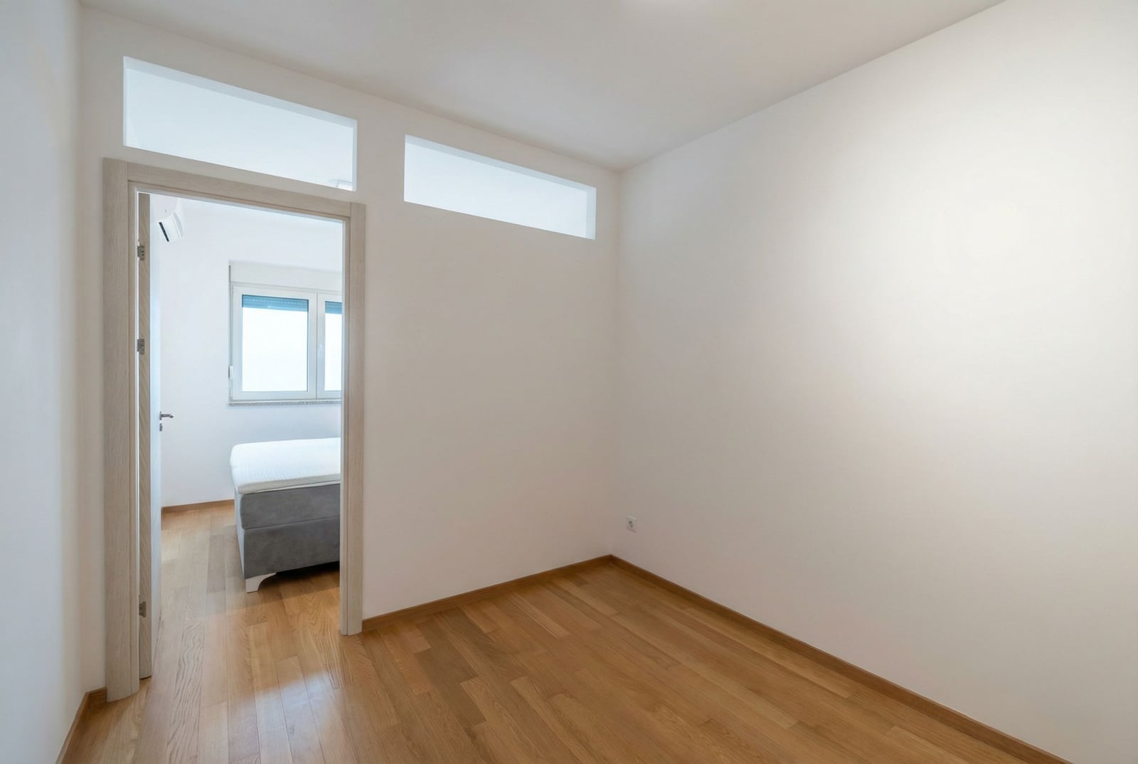 Bright empty room with parquet flooring and a view of the bedroom in an apartment in Bečići, Montenegro. Modern finishes.