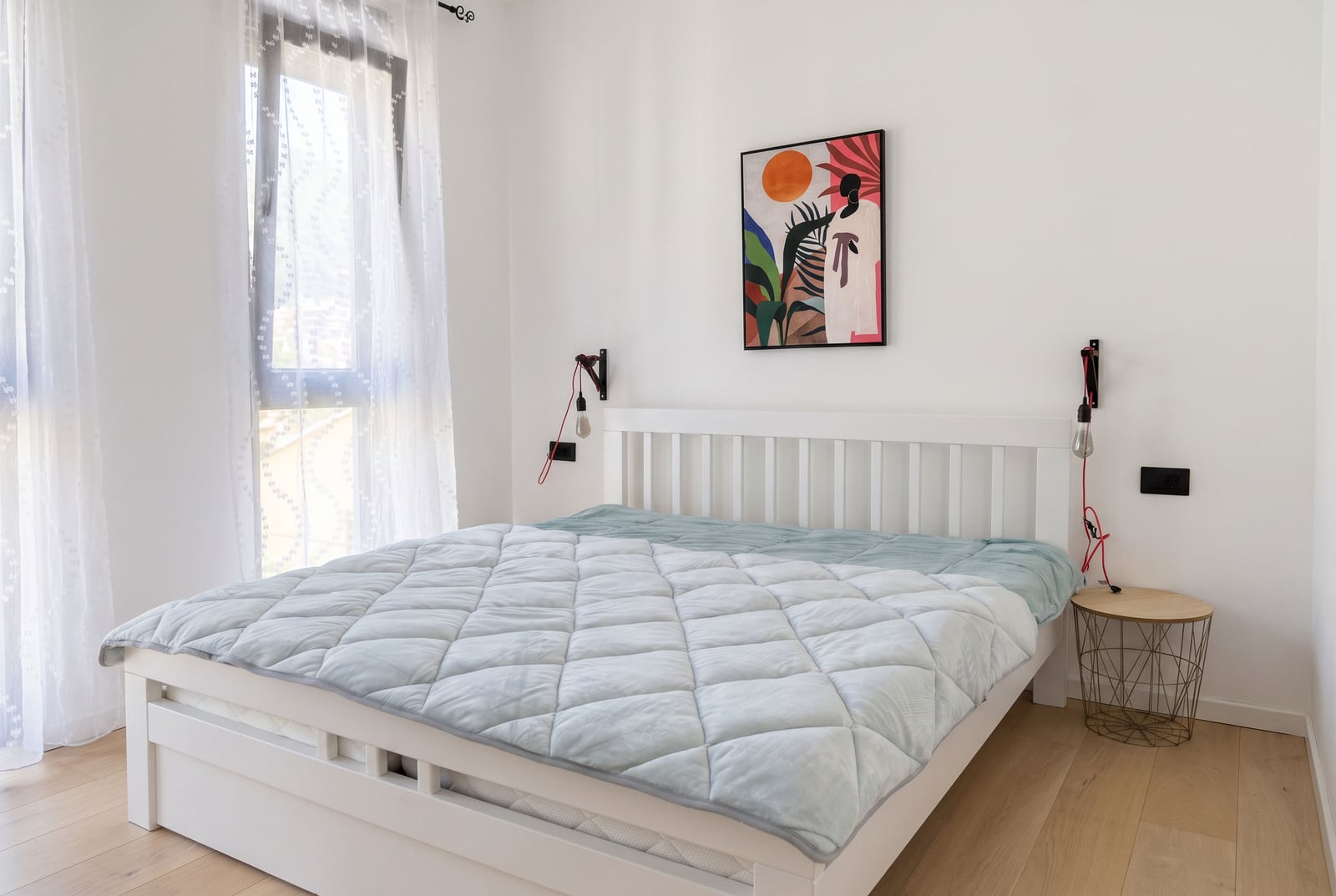 Bright bedroom with a white bed and a painting in an apartment in Tivat, Montenegro