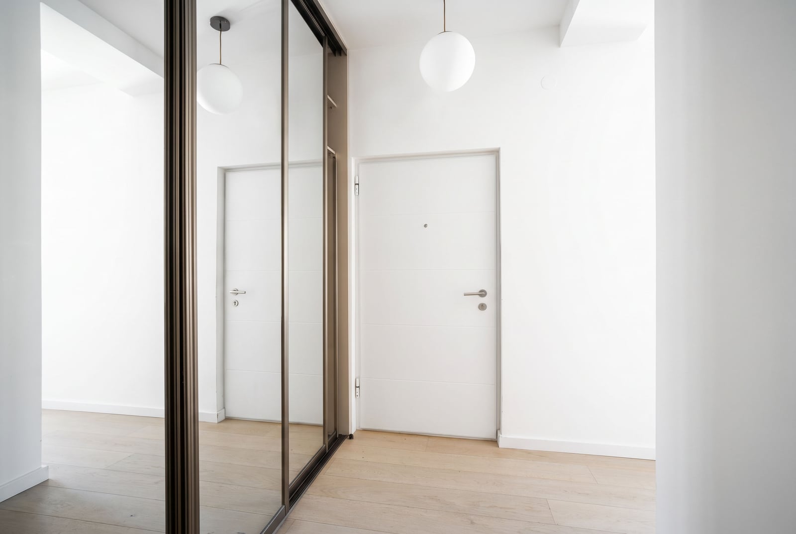 Modern hallway with light finishes, a mirrored wardrobe, and an entrance door in an apartment in Tivat, Montenegro.