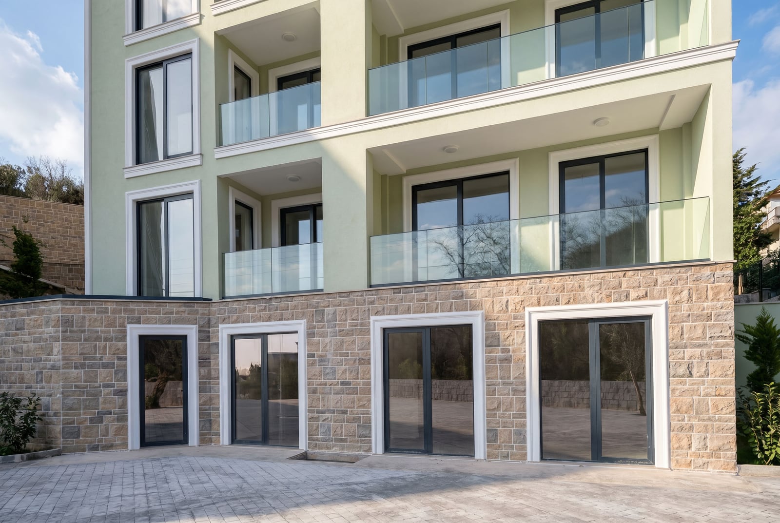 Modern residential building in Pržno, Montenegro: facade with stone cladding, panoramic windows, and glass balconies.