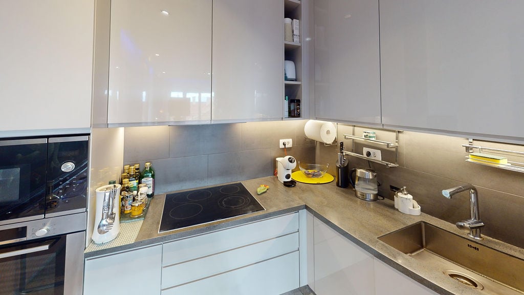 Modern kitchen in a townhouse, Luštica, Montenegro: glossy fronts, built-in appliances, and a stone countertop.