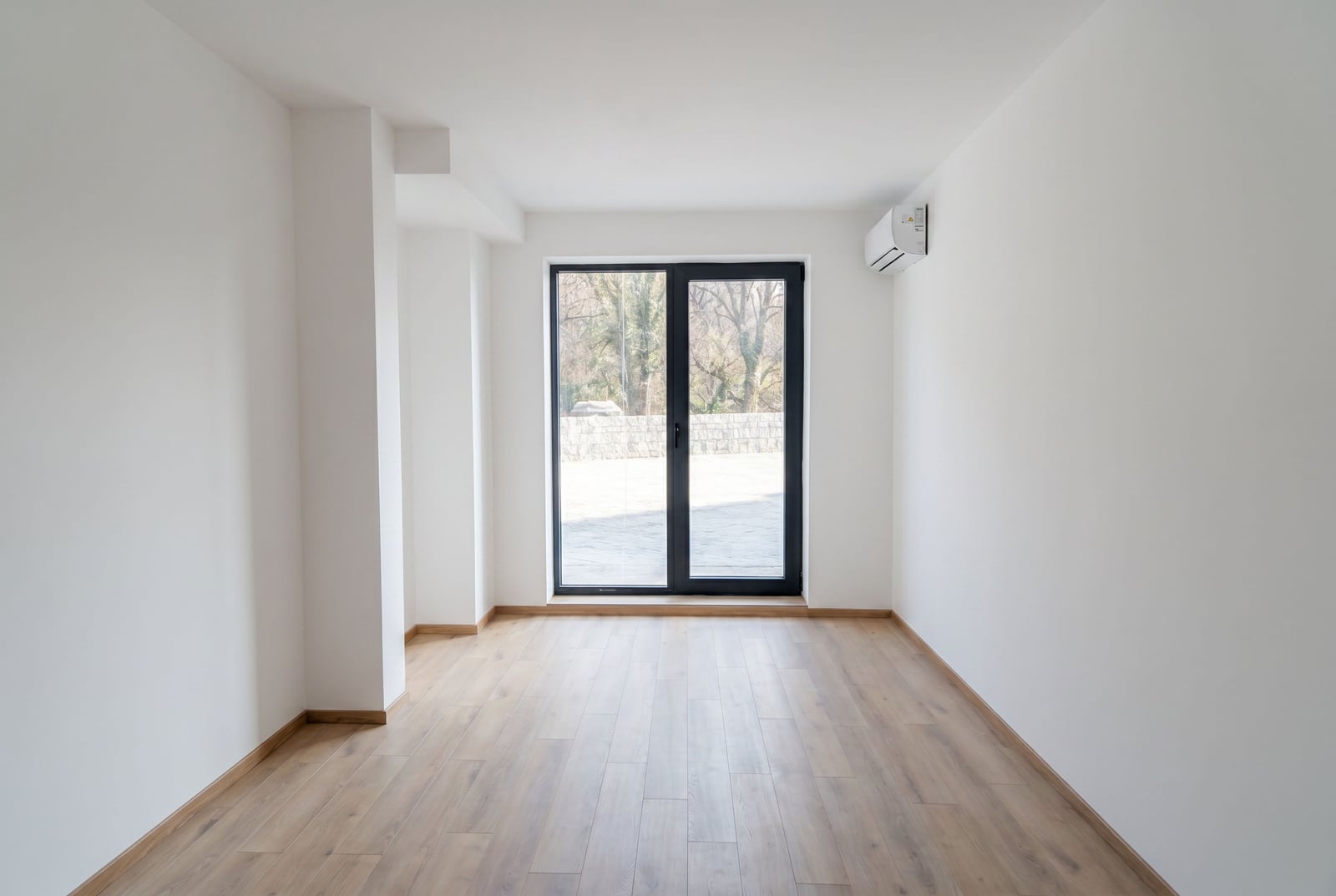 Bright living room with laminate flooring and a panoramic window in an apartment in Pržno, Montenegro. Modern interior with air conditioning.