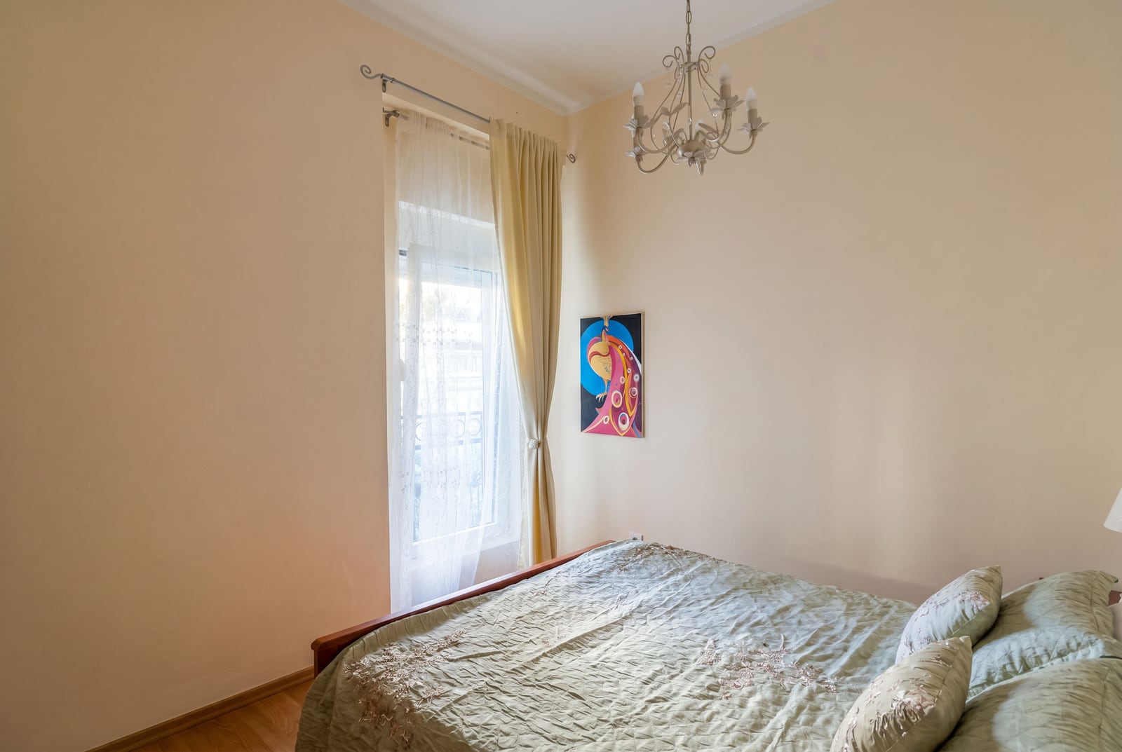 Cozy bedroom with a double bed and a classic chandelier in an apartment for sale in Budva, Montenegro.