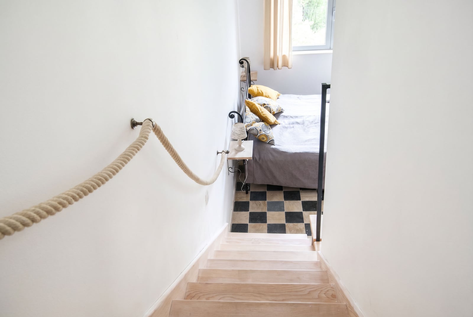 Top view of a bedroom with a wooden staircase and rope railings in an apartment, Risan, Montenegro.