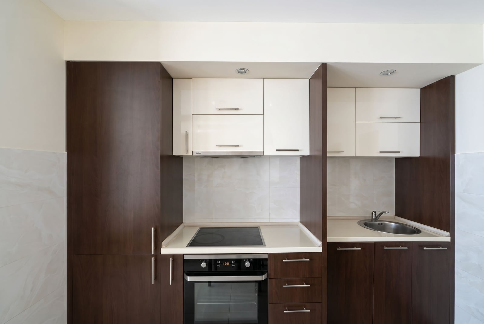 Modern kitchen in an apartment in Bečići, Montenegro: dark and white cabinetry, built-in stove, oven, and sink.